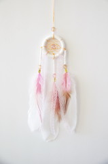 photo of a handmade white pink native american dreamcatcher with feathers, beads and lace