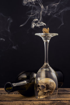 still life photography : candle and smoke over wine glass that cover the skull on old wood