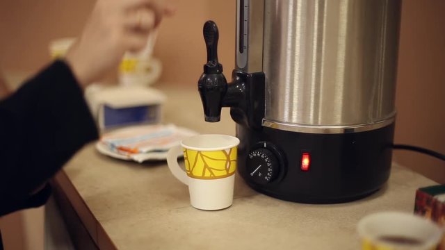 Pour boiling water from a thermos into a paper cup
