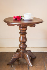 coffee and rose on retro wooden table near the wall of room in old house
