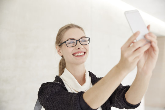 Smiling young woman with glasses taking a selfie