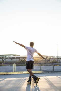 Man With Rollerblades And Arms Extended At Sunset