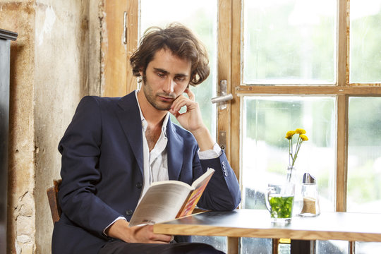 Young man in a coffee shop reading a book