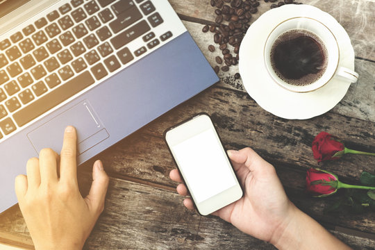 Coffee cup with hand using laptop and Mobile phone on old wood b