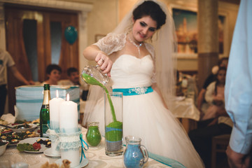 Bride is filling with the sand a vase