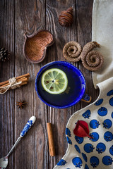 Tea with lemon and aromatic spices on wood background