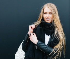 Portrait of a young beautiful blonde girl nex to black background. Spring, young, beauty. Outdoor. Warm color.