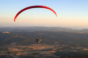 Paraglider holding ropes of orange flying wing in the air