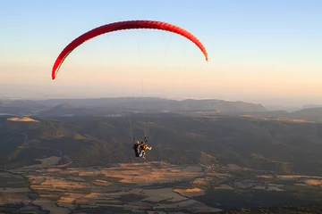 Crédence de cuisine en verre imprimé Sports aériens Paraglider holding ropes of orange flying wing in the air