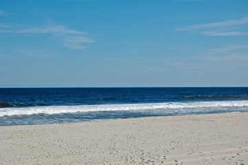 Sunny beach day, waves crashing and blue skies 