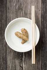 fake excrement in ceramic dish with plastic knife and fork on old wood