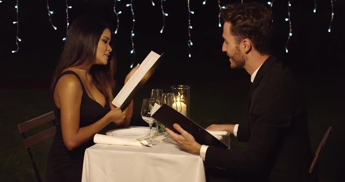 Young romantic couple reading the menu to order their food on a night out together dining at an upscale restaurant