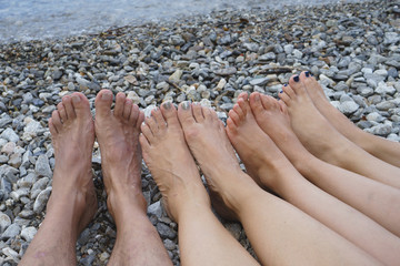Familie liegt barfuß am Strand, Füße in einer Linie