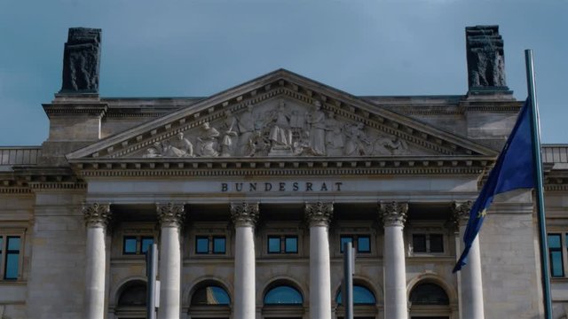 Real time locked down shot of Bundesrat building front facade in Berlin, Germany. EU flag is waving on the wind in front of Bundesrat. Medium shot.