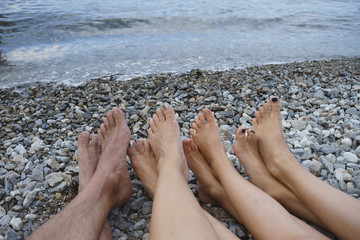 Familie liegt barfuß am Strand mit überkreuzten Beinen (2)