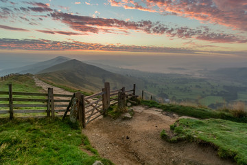 A vibrant sunrise at Mam Tor in the English Peak District with a wooden fence.