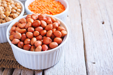 Close up of dried peanuts in a bowl on a wooden table.