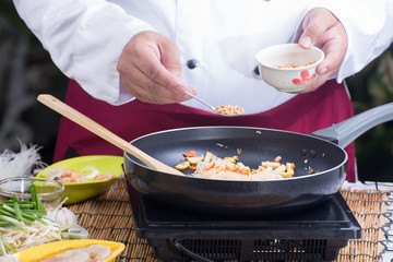 Chef putting crushed peanut to pan