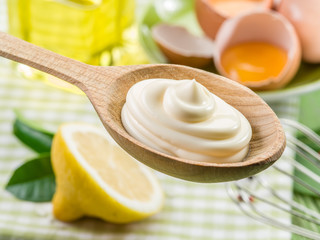 Natural mayonnaise sauce in the wooden spoon and its ingredient