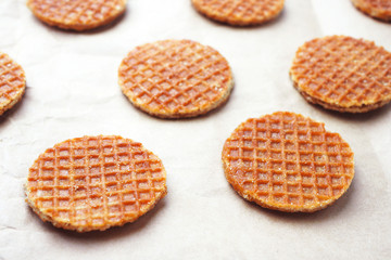 Close up of pattern of caramel dutch waffles on a waxed paper.