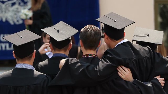 University friends hugging, posing for picture together, graduation ceremony