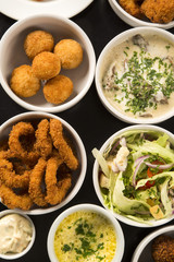 Mixed brazilian snacks, including pastries, fried chicken, salad