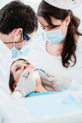 Dentist treating woman patient with drill