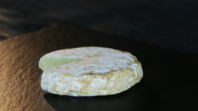 Rotation cheese on black slate plate. Delicious cheese Camembert on the cutting board on black background