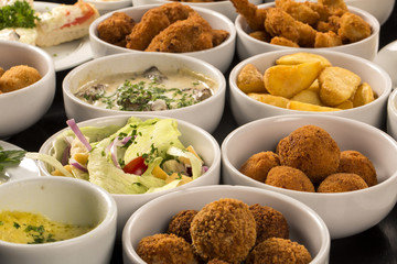 Mixed brazilian snacks, including pastries, fried chicken, salad