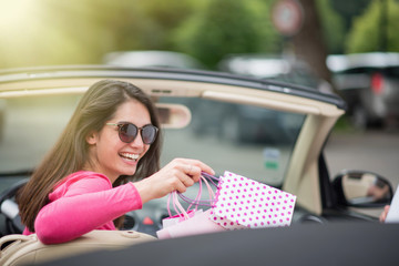 Cheerful woman in her convertible car depositing shopping bags