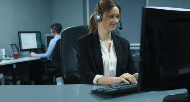 4K: Zwei weibliche Callcenter Angestellte arbeiten mit Headsets am Computer. Sie sind sehr freundlich und haben Spa&szlig; bei der Arbeit, um dem Kunden bei der Problem L&ouml;sung zu helfen.