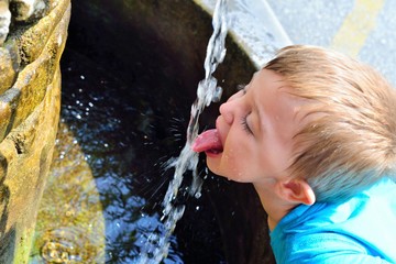 A boy drinks water from a spring