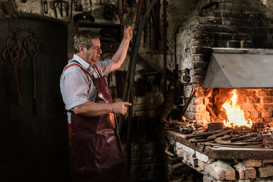 Blacksmith pumping air to kindle fire using bellows