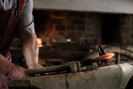 Blacksmith working on hook using hammer and thorn