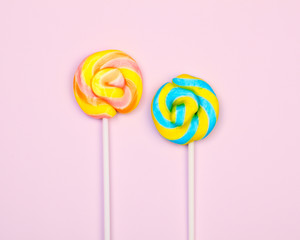 Flat lay. Two colorful lollipops on a pink background