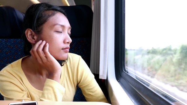 Young woman takes the train. Passengers traveling on the train looking out the window at the passing landscape. 