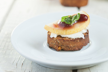 Bruschetta with goat cheese and pear on white plate