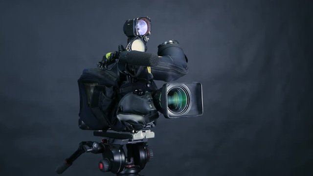 Professional digital video camera, camcoder isolated on black background in tv srudio. 4K.