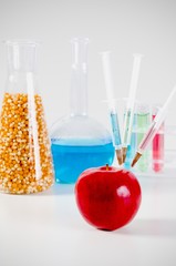Three syringes in red apple. Genetically modified food concept.
