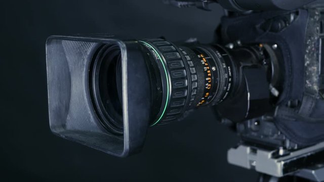 Movement along professional studio camera, casmcoder standing in TV studio ready for broadcasting. 4K.