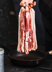Pork belly meat on hook. Fresh bacon sliced on hand. 