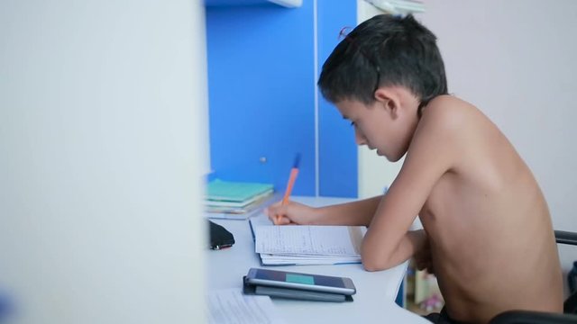 Teenage boy doing homework using a cell phone. natural video