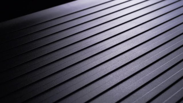 Light Shines Over Diagonally Grooved Metal and Camera Slowly Pans to Right, Macro