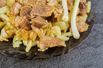 A plate of fried meat with potatoes on a black stone table