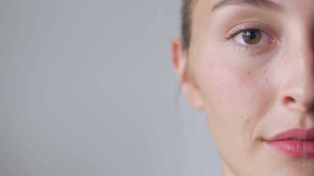 A young blond haired woman smiles with only half her face shown