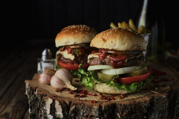 Two beef burgers on a dark background.