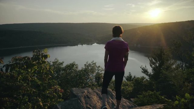 Woman stands on the mountain rocks and admiring a buatiful view