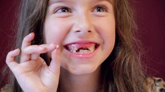Excited little girl beaming with pride after pulling her own tooth.