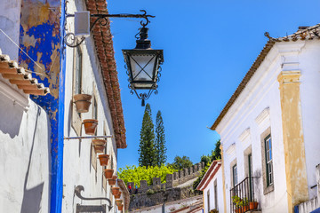 Fototapeta na wymiar Narrow White Street 11th Century Castle Wall Lamp Obidos Portugal