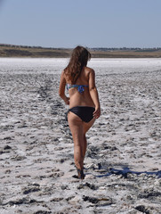 Fototapeta na wymiar Woman walking along the dry bottom of a salt lake, rear view